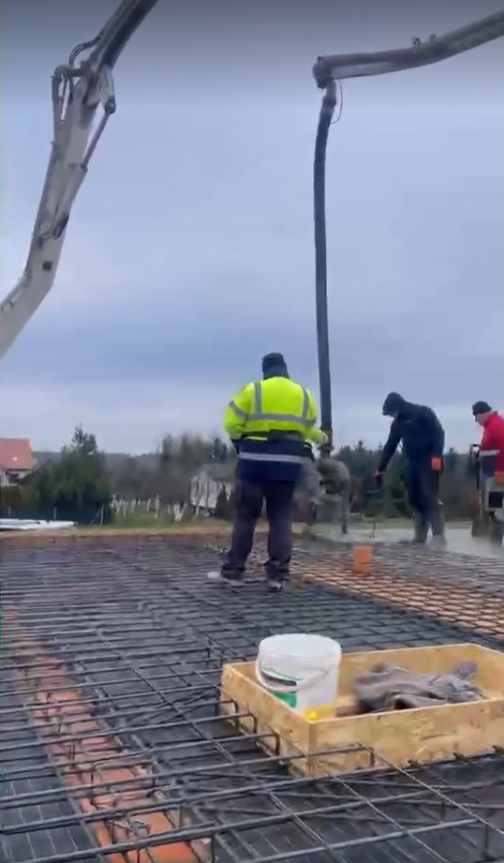 Ekipa betonuje zbrojony strop pompą do betonu na budowie domu